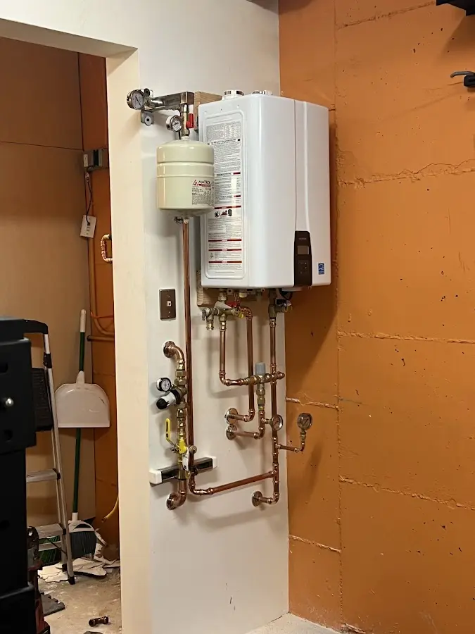 Plumbing technician inspecting water heater connections in Wapakoneta